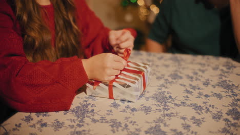 Mujer-Atando-Cinta-En-Caja-De-Regalo-Sentada-Por-Un-Amigo