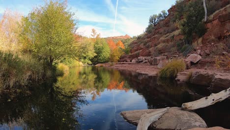 Das-Wasser-Eines-Langsam-Fließenden-Baches-Spiegelt-Das-Prächtige-Herbstlaub-Und-Die-Roten-Felsen-Von-Nordarizona-Wider