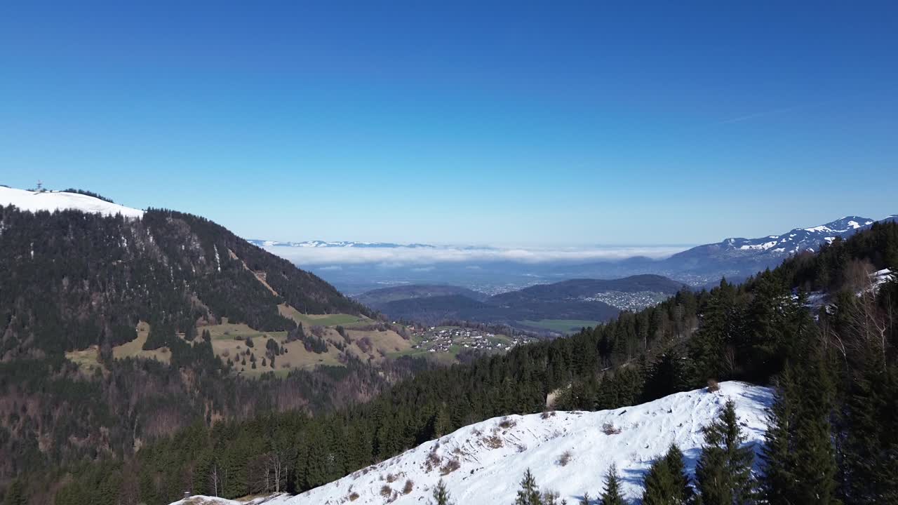 Drone fly along mountain road in winter in austria with amazing view over small towns far away