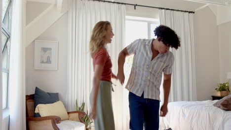 diverse couple dancing joyfully at home, enjoying lively and fun moment together