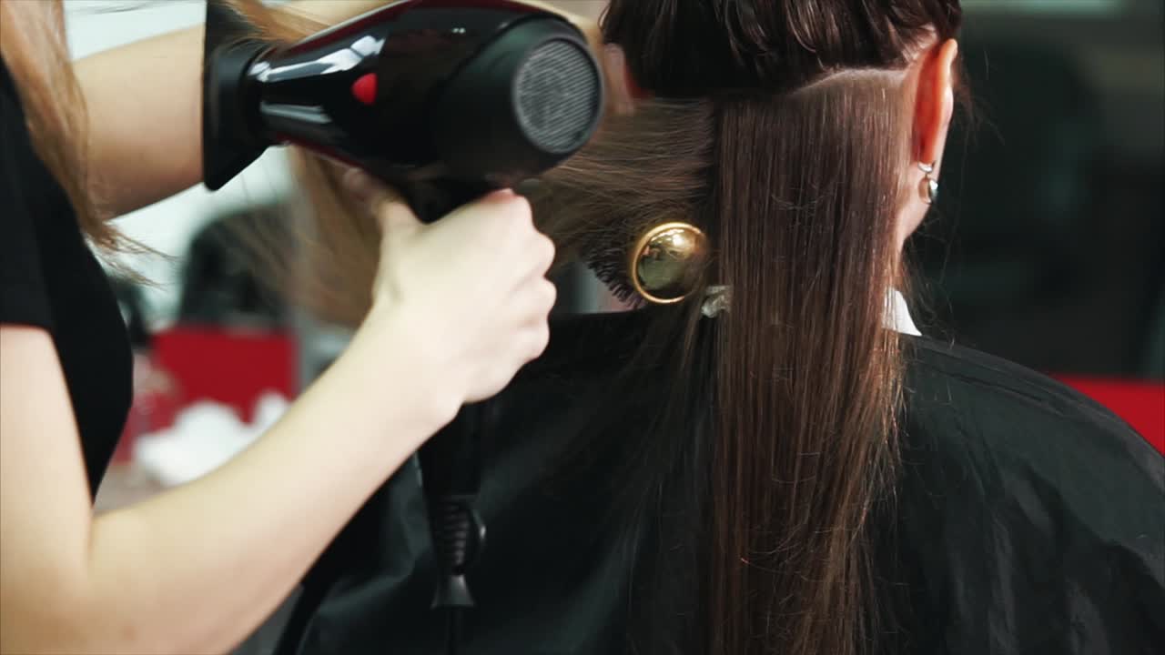 Parrucchiere che asciuga e acconcia i capelli di una donna