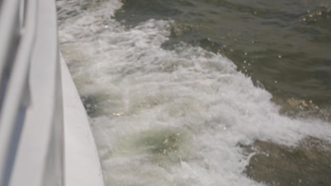 waves splash alongside wake of boat, slow motion depth of focus