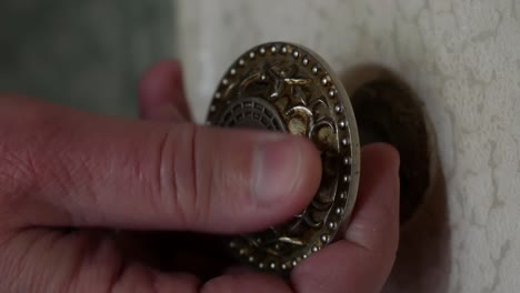 a man's hand touches a round metal doorknob. a man opens a wooden door painted