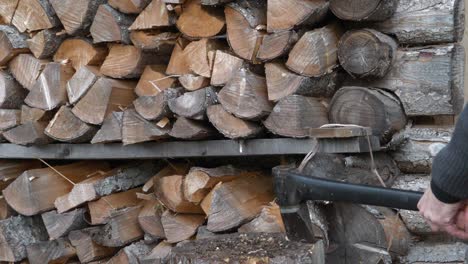 chopping a firewood log with stacked firewood wall background