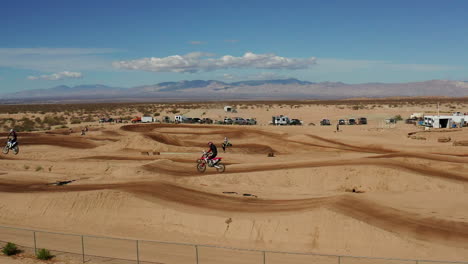 two motocross racers jumping over ramp in mojave desert landscape track, aerial