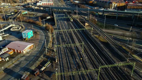 Train-Travelling-At-Railroad-Track-With-City-Traffic-At-Sunset-In-Gothenburg,-Sweden