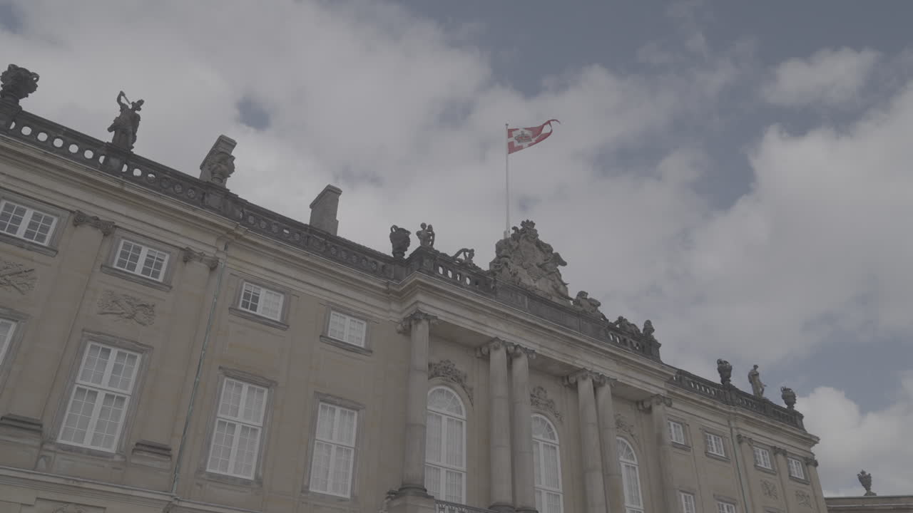 Danish flag waving in the wind on top of the Royal Palace in Copenhagen Denmark on a cloudy dayLOG