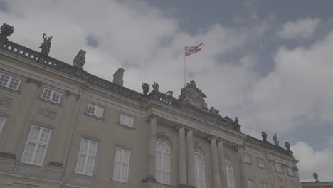 danish flag waving in the wind on top of the royal palace in copenhagen denmark on a cloudy daylog