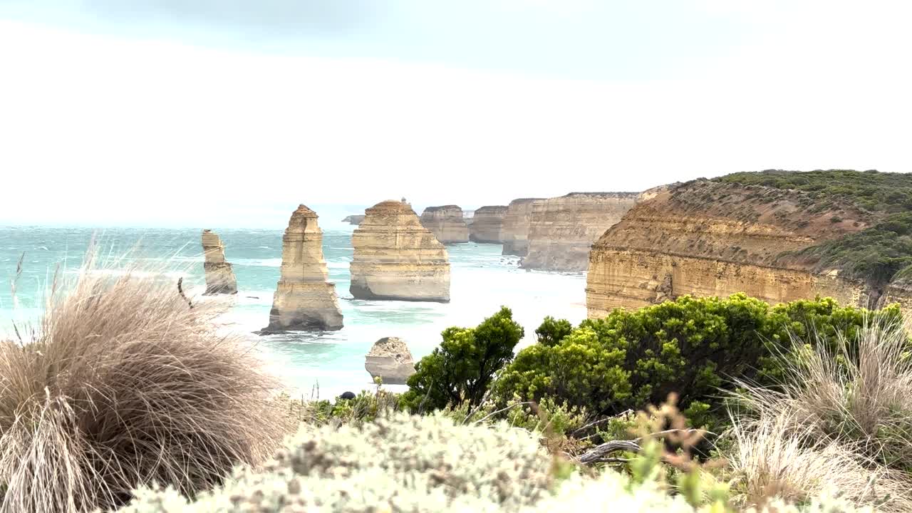 Breathtaking coastal landscape with limestone stacks, vibrant vegetation, and dynamic ocean waves under bright daylight
