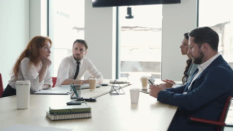 a red-haired businesswoman gives directions to her work team in a business meeting