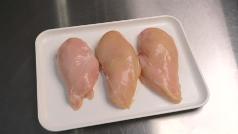 fresh chicken meat is lying on a tray, ready for further processing