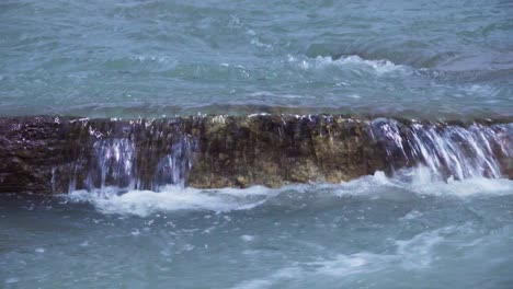 river water flows over a stone, thus shaping it over time