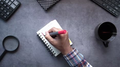 person writing a to-do list at a desk