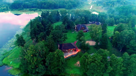 luxury countryside, lakeside homes with lights illuminating the deck at dusk - aerial reveal of the landscape