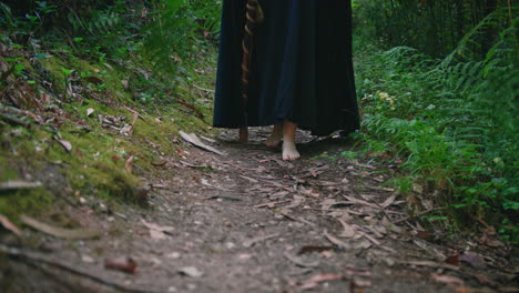 young druid girl walking in a forest feet detail dolly long shot