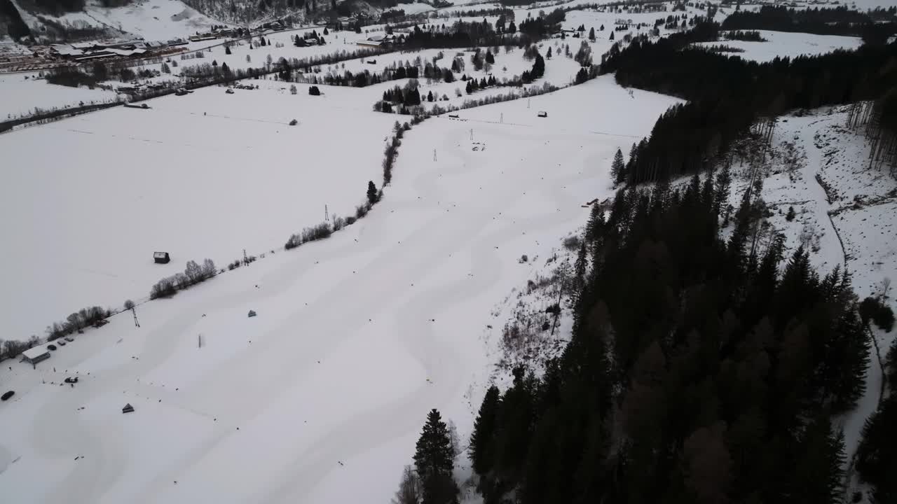 어두운 숲과 함께 언덕 근처의 눈이 인 닫힌 경주 트랙의 공중 풍경
