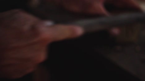 close-up-of-country-man's-hands-working-with-wood-in-his-old-workroom-on-a-wooden-workplace-at-night-with-a-smooth-warm-light