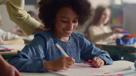 Alumno-Haciendo-Trabajo-De-Clase-En-El-Escritorio.-Maestra-Ayudando-A-Niña-Con-La-Tarea-De-La-Lección