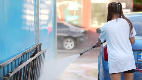 mujer lavando un coche en un lavado de coches al aire libre