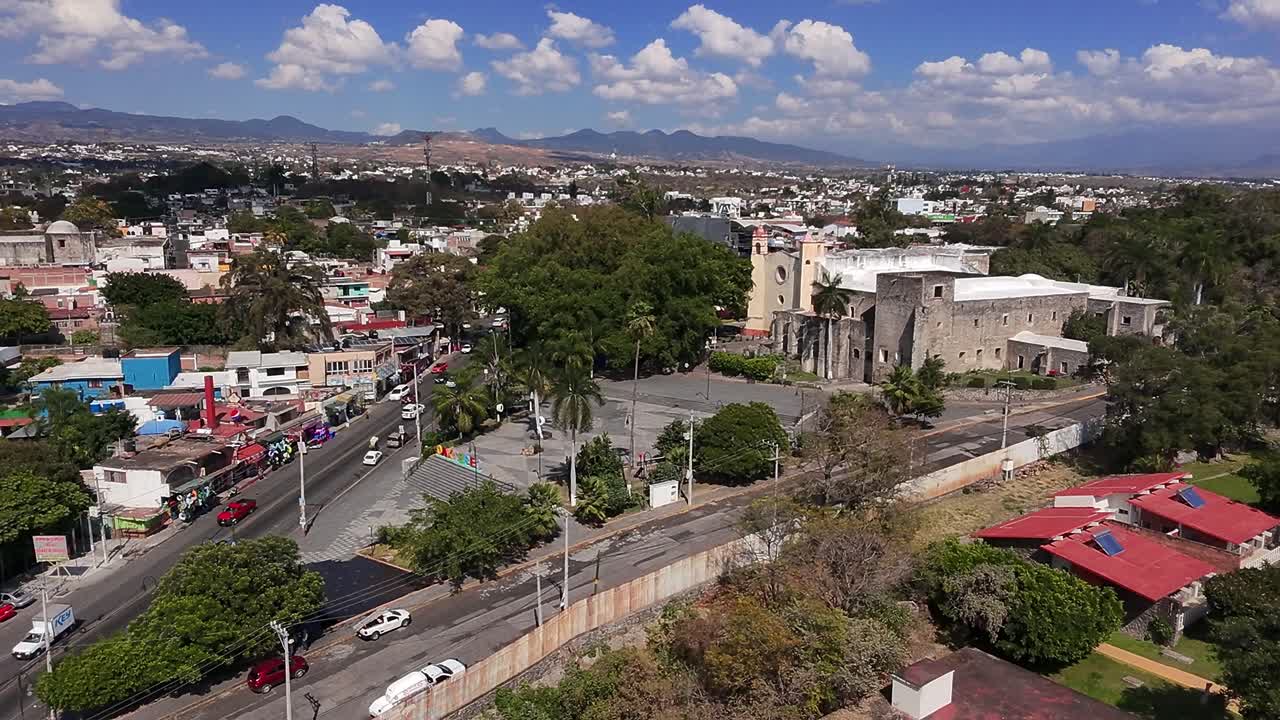 Aerial: Oaxtepec city sign during the day with cityscape and blue sky in Morelos, Mexico, establishing drone shot