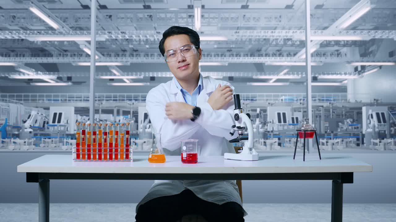 아시아인 과학자가 실험관 위에 있는 현미경을 통해 보고, 미소 짓고, 실험실에서 작업하는 동안 팔을 고, 현미경으로 플을 분석하는 실험실에서 일하고 있다.