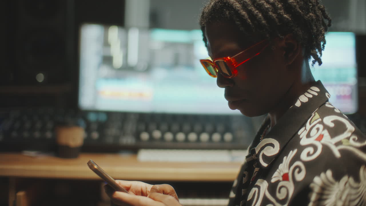 African American Musician Using Smartphone in Recording Studio