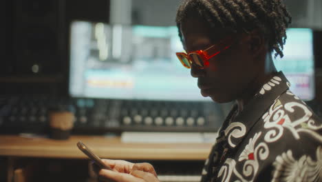 african american musician using smartphone in recording studio
