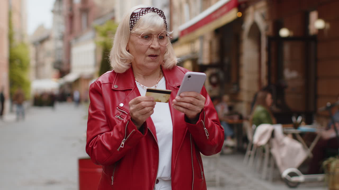 Senior woman using credit bank card smartphone while transferring money purchases online shopping