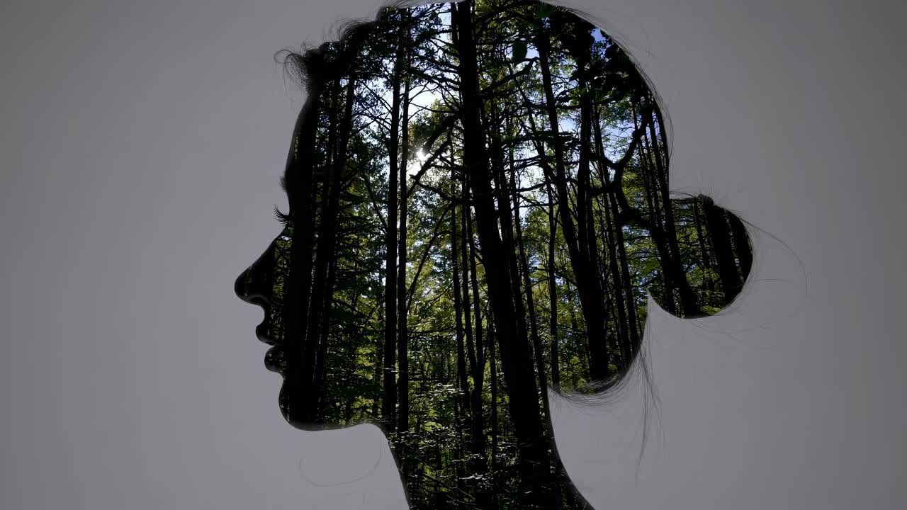 Double exposure of a woman's profile with a forest scene, shot from a side angle
