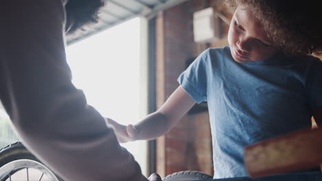 close up of pre teen boy standing at a workbench concentrating on screwing in a bolt while building a racing kart with his father, selective focus