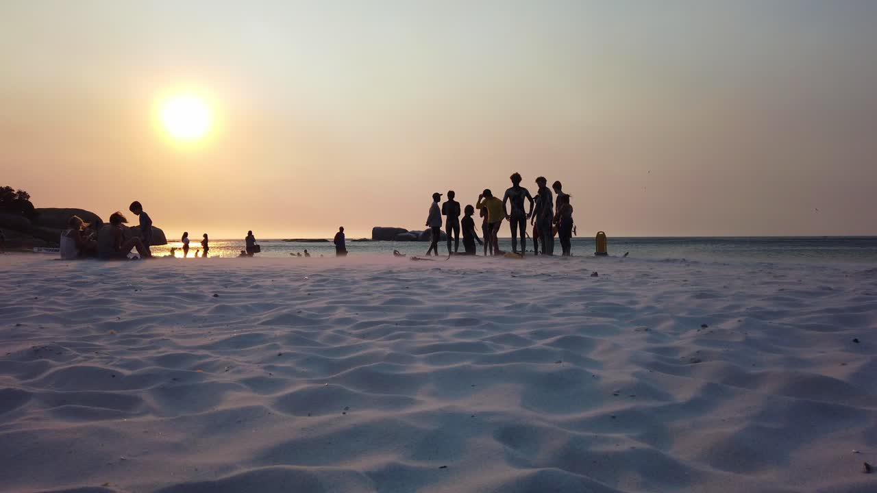 A silhouette of  people on the beach enjoying the water and learning to surf.