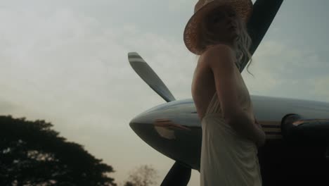 woman in vintage dress near airplane at sunset