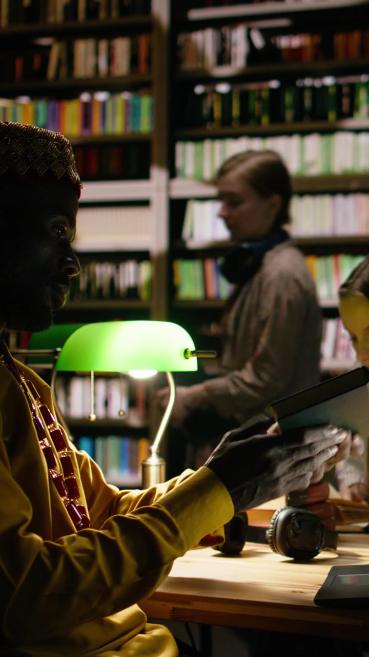 Vertical Video Side View Of Black Man In Traditional Clothes Typing On Laptop At Library Desk