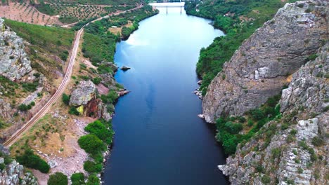 aerial-shot-of-deep-blue-river-flowing-through-steep-valley,-4k