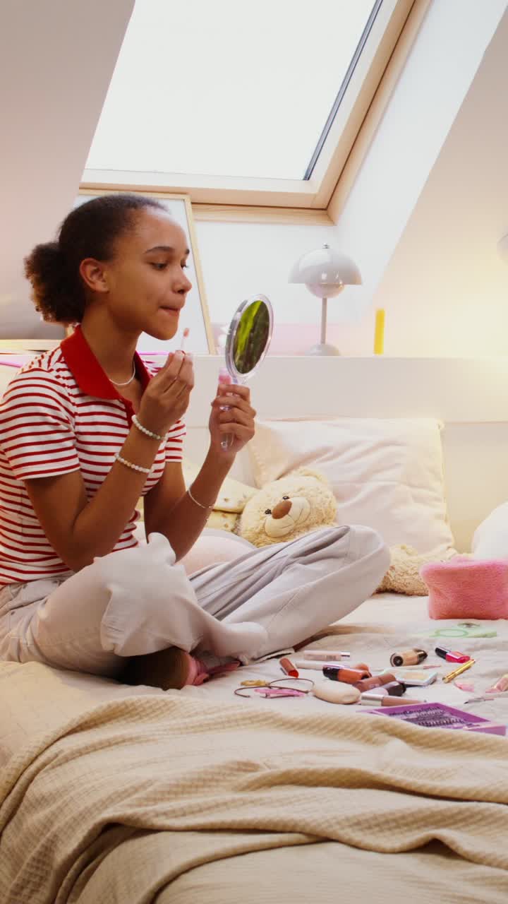 una adolescente aplicando maquillaje en su dormitorio