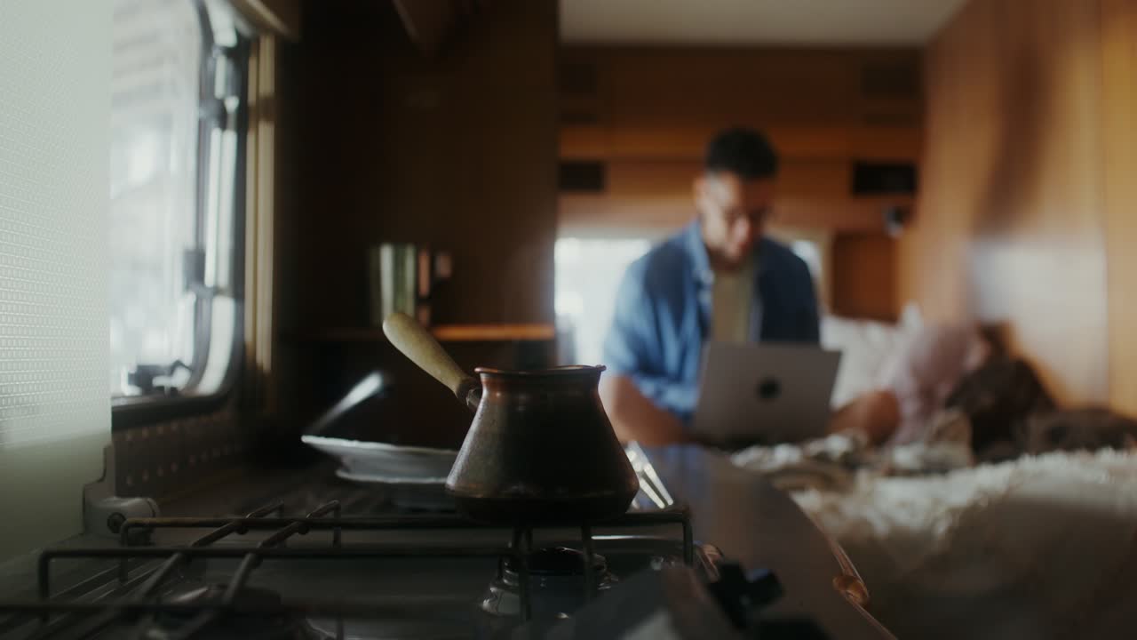 Uomo che lavora al laptop in camper con caffè