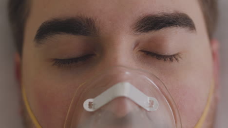 close up of a sick man lying on bed breathing through oxygen mask 2