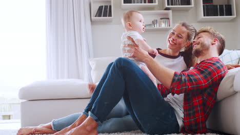 Young-white-couple-sitting-with-baby-at-home,-side-view