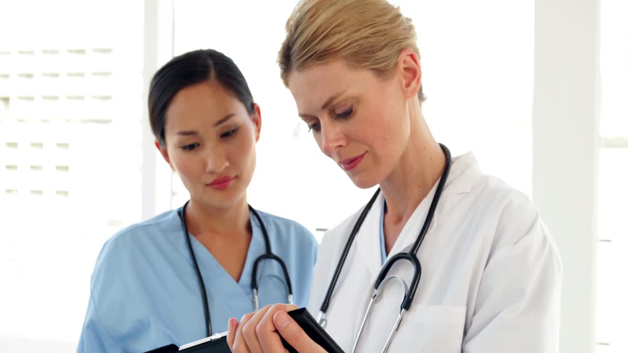 두 의사가 파일을 보고 카메라를 쳐다보고 있습니다.