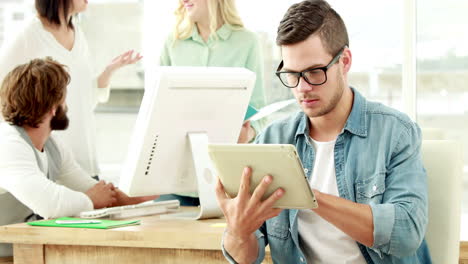 hombre de negocios casual usando la tableta delante de sus colegas