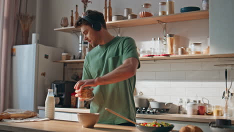man listening music cooking in wireless headphones at modern kitchen closeup