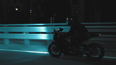 a man rides a sports motorcycle through the city at night