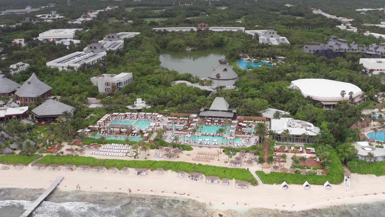 Ripresa aerea in discesa e con inclinazione verso l'alto del beach club privato in un resort di lusso nella Riviera Maya, Messico. 4K