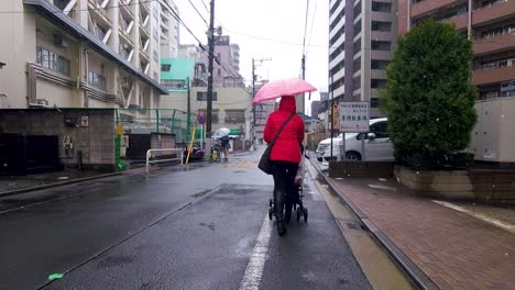 following shot of woman pushing stroller down back lane in tokyo japan asia on snowy day.