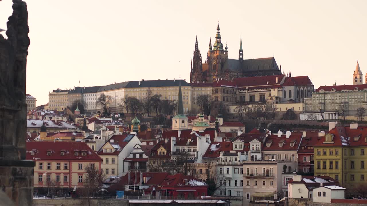 Zamek Praski i historyczne centrum o zachodzie słońca, z mewami latającymi poniżej