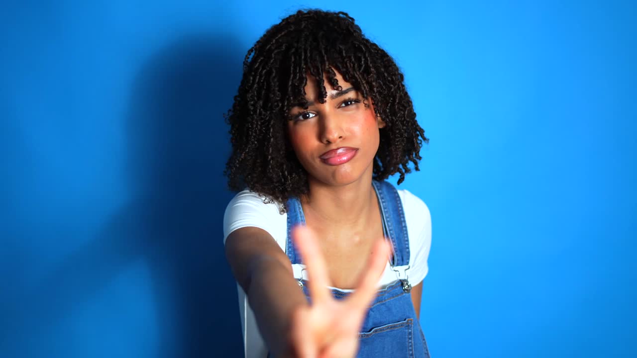Young woman making a peace sign on a blue background