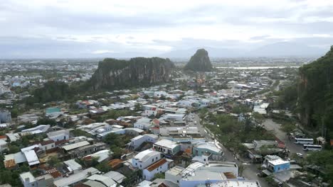 Heavenly-aerial-shot-of-an-asian-city-deep-in-the-green-lush-mountains-during-an-overcast-day