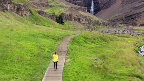 young woman walking in front of a waterfall