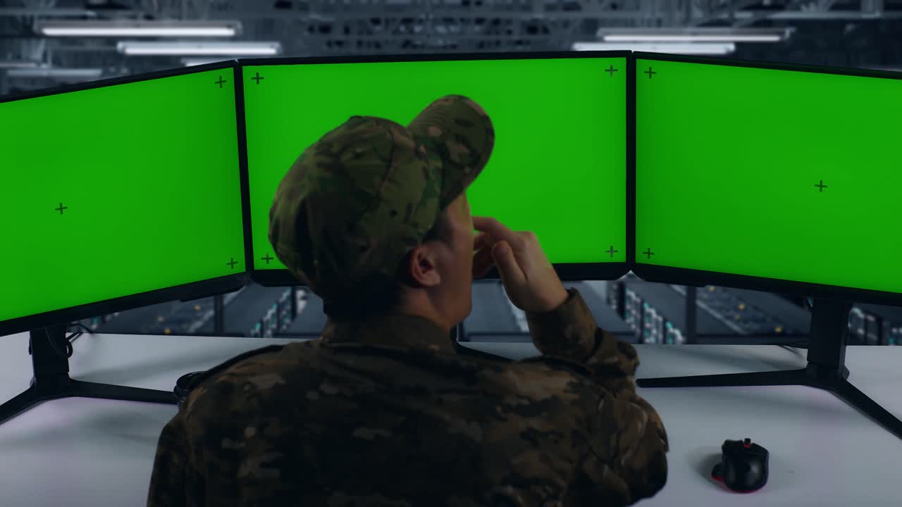 vista trasera de un militar asiático cansado bostezando mientras trabajaba con un simulacro de varios monitores de computadora en el centro de datos