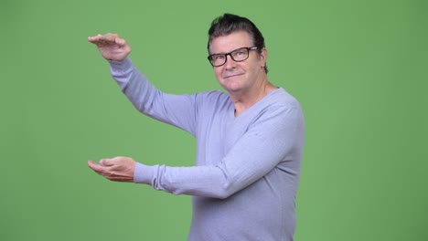 hombre viejo y guapo mostrando algo.